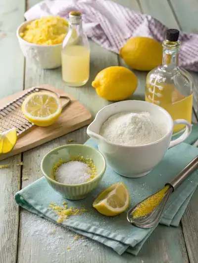 Flat lay of ingredients for homemade lemon drops including sugar, corn syrup, lemon juice, and zest on a wooden table.